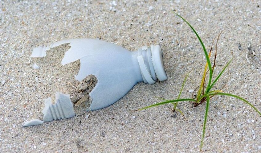 Zersetzte Plastikflasche im Sand