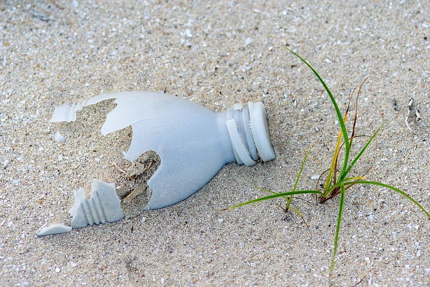 Damaged plastic bottle in sand